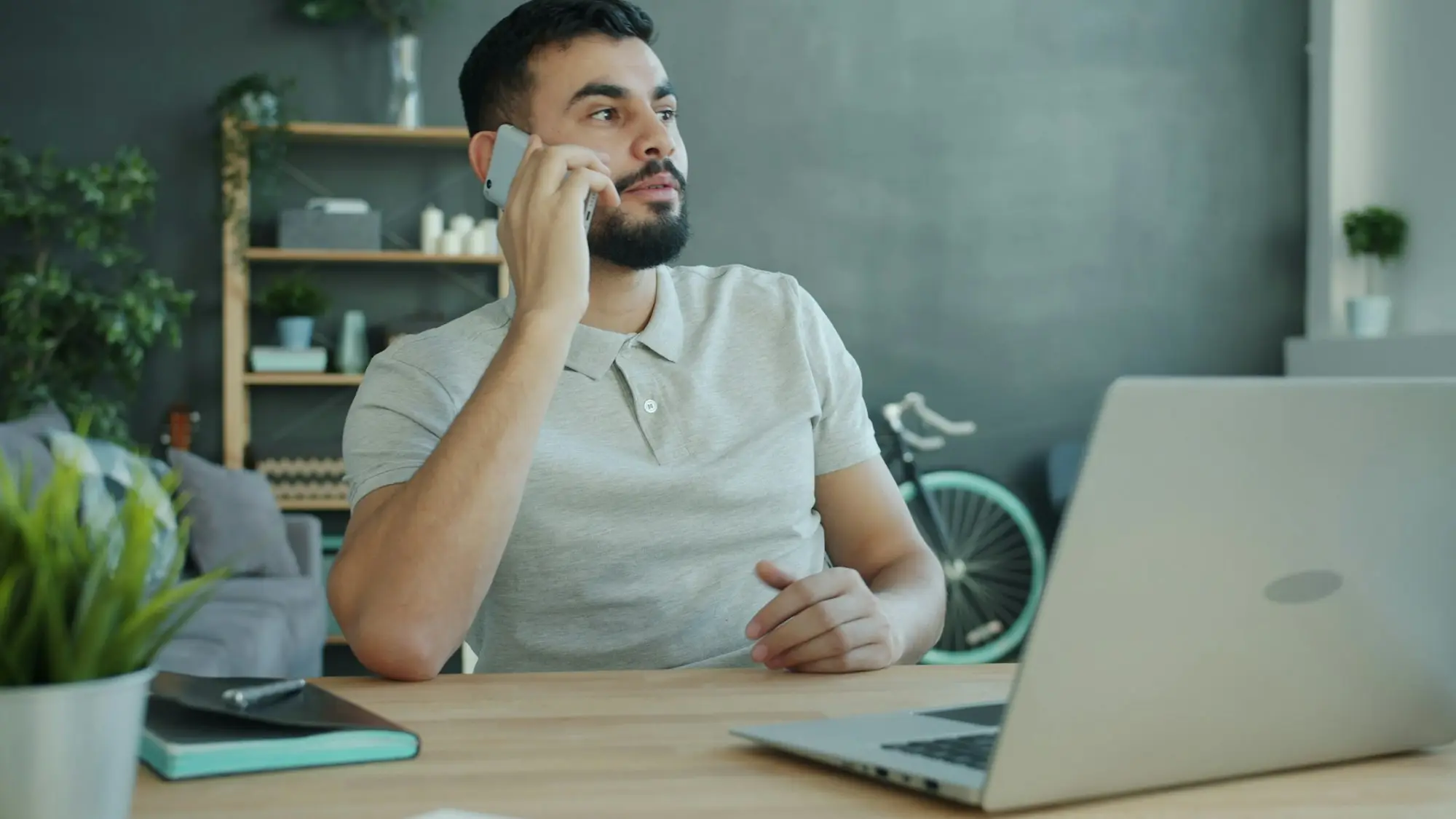 Man talking on the phone at a desk with a laptop